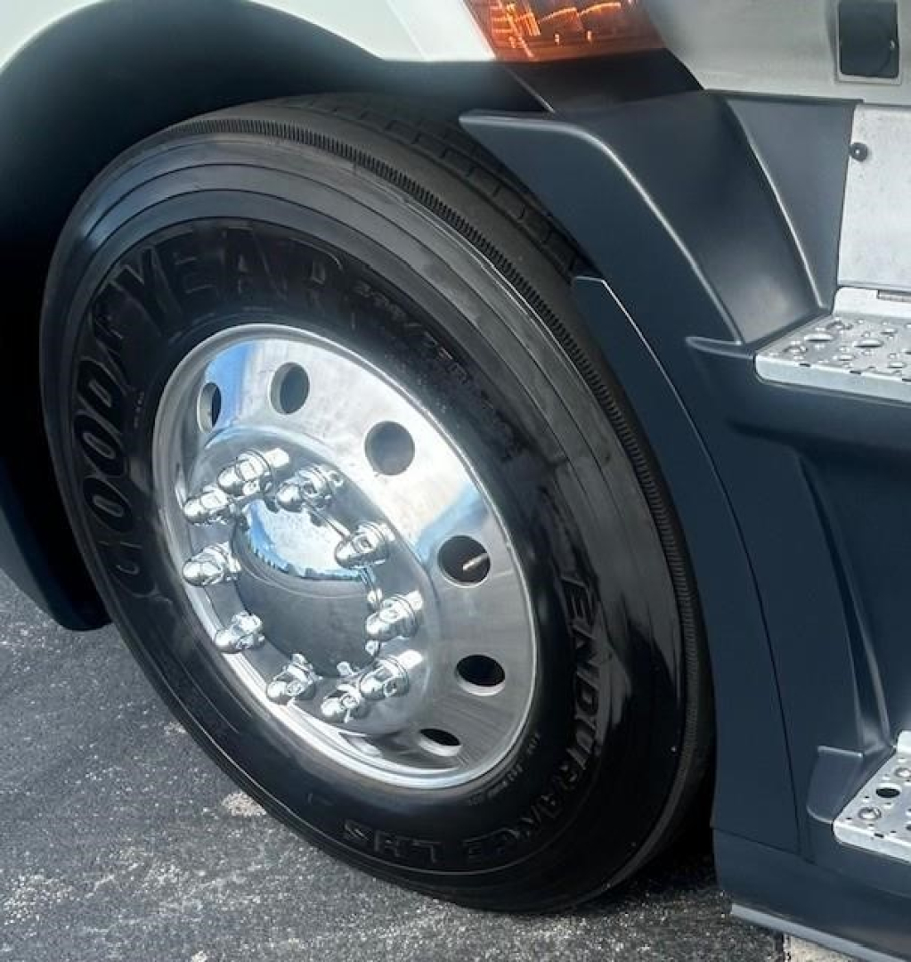 Truck wheel and fender showing Goodyear tire and polished steel hubcap near the front of a Freightliner Cascadia 116.