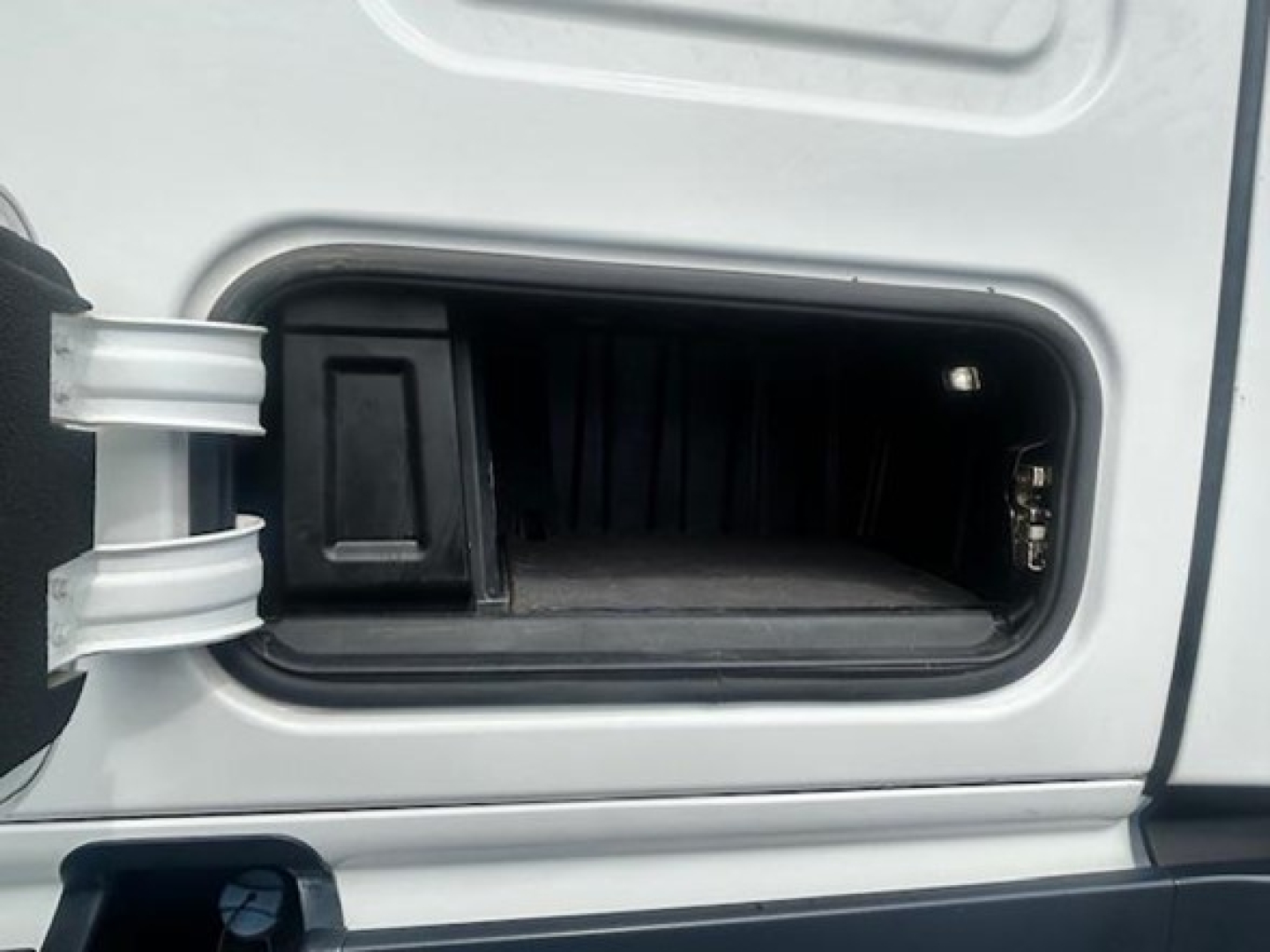 Truck cab door storage compartment with open fuel or DEF filler area? No, this image shows a small under-cab storage pocket recessed into the sleeper cab area of a Freightliner Cascadia.