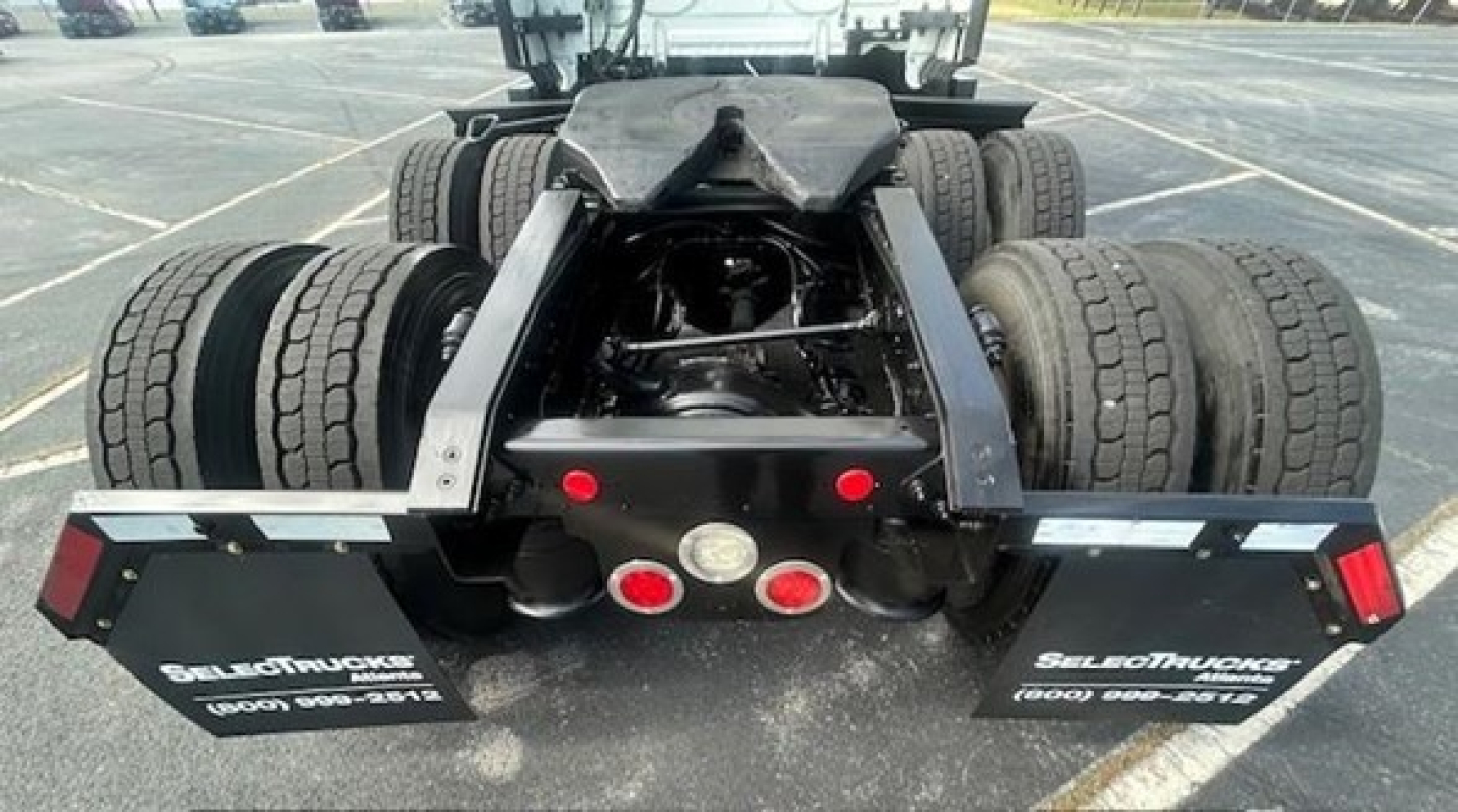 Freightliner Cascadia rear view showing twin axle dual wheels, fifth wheel and rear bumper with reflectors and mud flaps.
