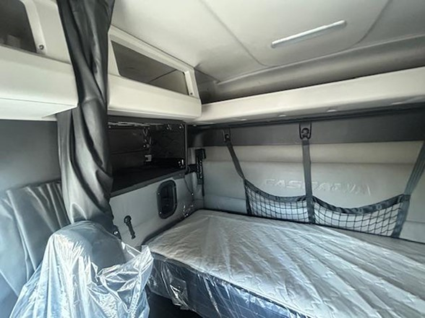  sleeper cab interior showing bunk bed with net storage and overhead shelf in a Freightliner Cascadia cab