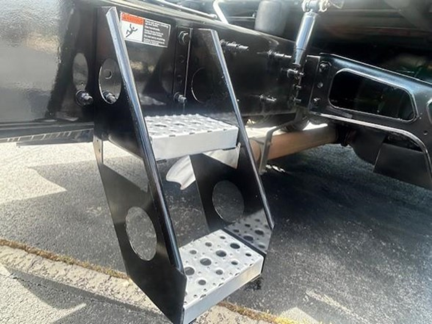 Truck step/ladder bracket on Freightliner Cascadia showing perforated steel steps and side mounting plates.