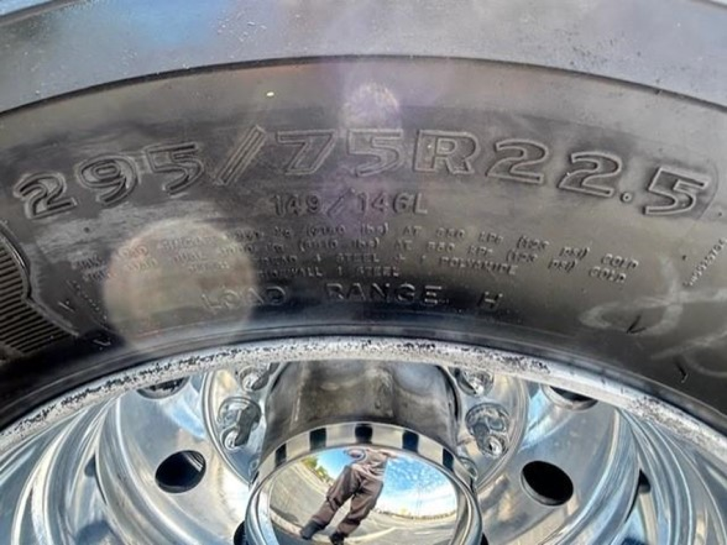 Tire sidewall showing size 295/75R22.5 on a steel wheel with reflections and of a Freightliner Cascadia component labeling.