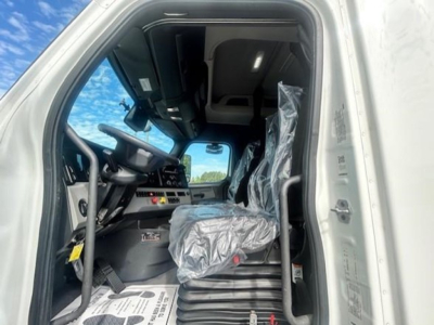 Cab interior of a 2022 Freightliner Cascadia 116 sleeper truck showing steering wheel, dashboard controls, and driver seat wrapped in plastic.