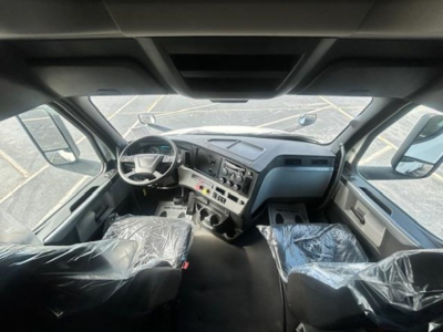 Cabin interior of a 2022 Freightliner Cascadia 116 truck with wrapped seats and dashboard; steering wheel, gauges, and center console visible.