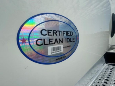 Freightliner Cascadia 116 side door area showing CERTIFIED CLEAN IDLE sticker on light-colored body.