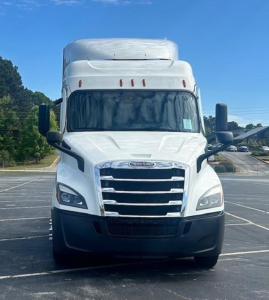 Truck front view showing Freightliner Cascadia 116 grill and headlights with white cab in parking lot.