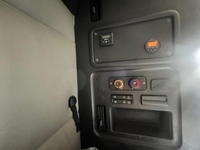 Cab interior of a Freightliner Cascadia sleeper showing dashboard panel with switches, gauges, and circular vents visible.