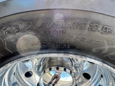 Tire sidewall showing size 295/75R22.5 on a steel wheel with reflections and of a Freightliner Cascadia component labeling.