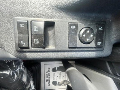 Truck interior control panel with window/lock switches and circular joystick on driver door, plus a footwell card visible
