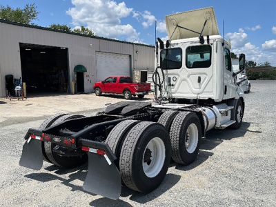 tractor truck rear view showing fifth wheel and dual rear axles with mud flaps and wheel tires in a lot
