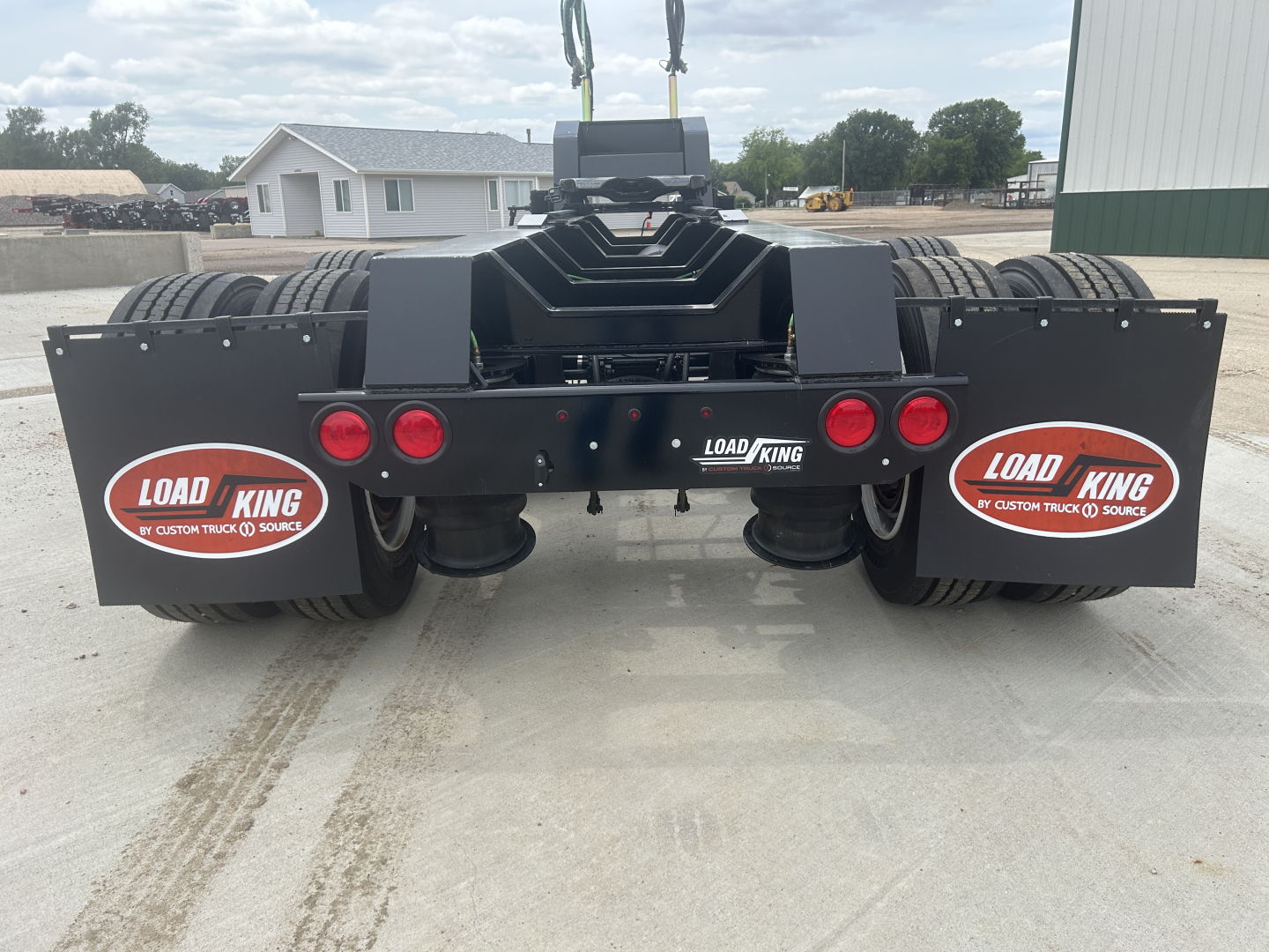 Load King HD702G trailer rear view showing dual axles with black mudflaps, red taillights, and Load King branding stickers on each side.