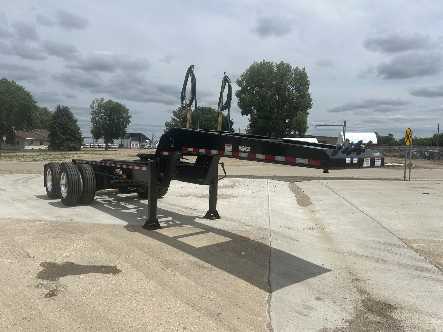 Load King HD702G trailer/dolly with extended gooseneck and dual axles, black frame, in-service with stabilizing legs deployed.