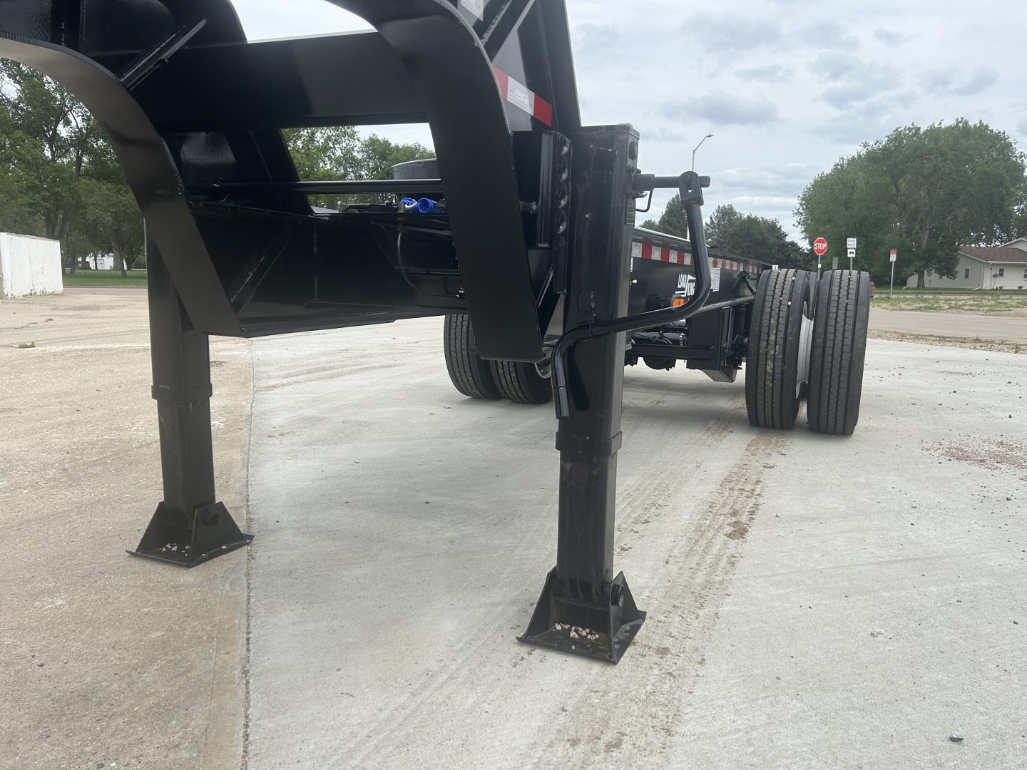 Load King trailer dolly legs and chassis visible with stabilizing jack stands, hydraulic framing, and wheel axles. No legible serials or model numbers readable.