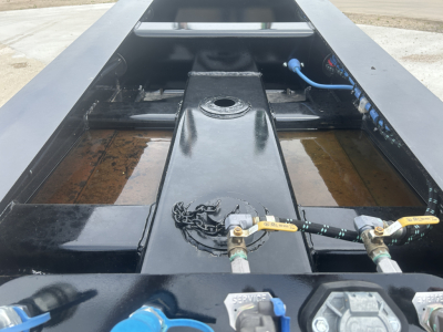 HD702G trailer chassis and center section with hydraulic connections and control hoses visible in a dolly trailer bed.