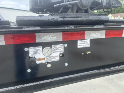 Load King HD702G trailer x-ray view showing control panel with labels, gauge, and warning stickers on black frame; red reflective tape along edge.