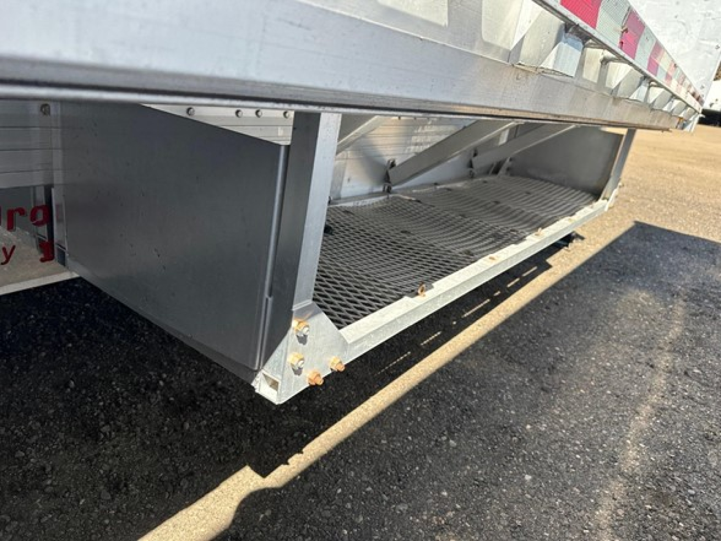 Low-angle view of a 2018 Reitnouer All Aluminum Drop Deck trailer showing the underside, aluminum decking, side step and grated access near the lower edge.