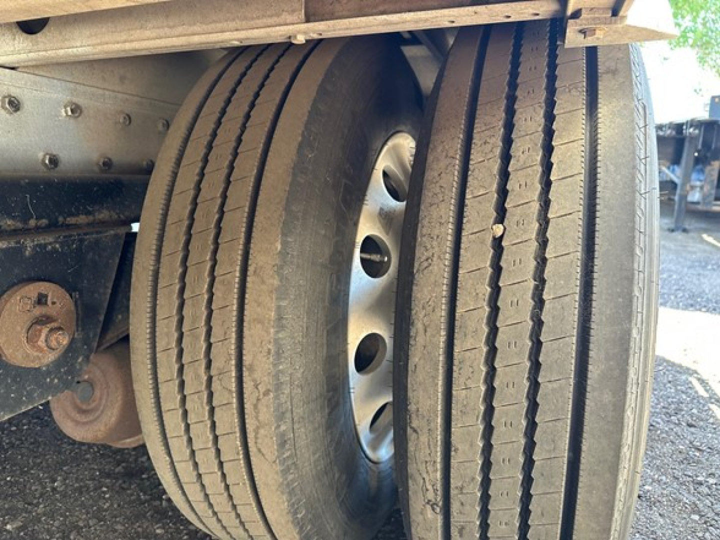 Rear view of a 2018 Reitnouer all aluminum drop deck trailer, dual rear wheels with hub, dual tires, and part of the frame; visible components include wheel rims, bolts, and a rust-colored bracket.