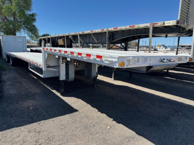All-aluminum drop deck trailer with long flatbed sections and a ramp, side safety rails, and reflective red/white tape along edges.