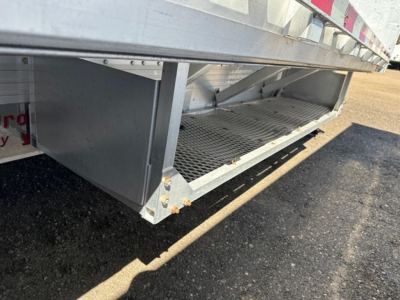 Low-angle view of a 2018 Reitnouer All Aluminum Drop Deck trailer showing the underside, aluminum decking, side step and grated access near the lower edge.