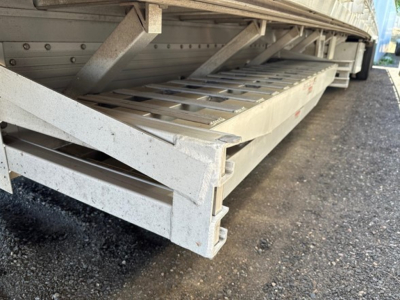 All-aluminum drop deck trailer side view showing edge of ramp and stacked deck plates.