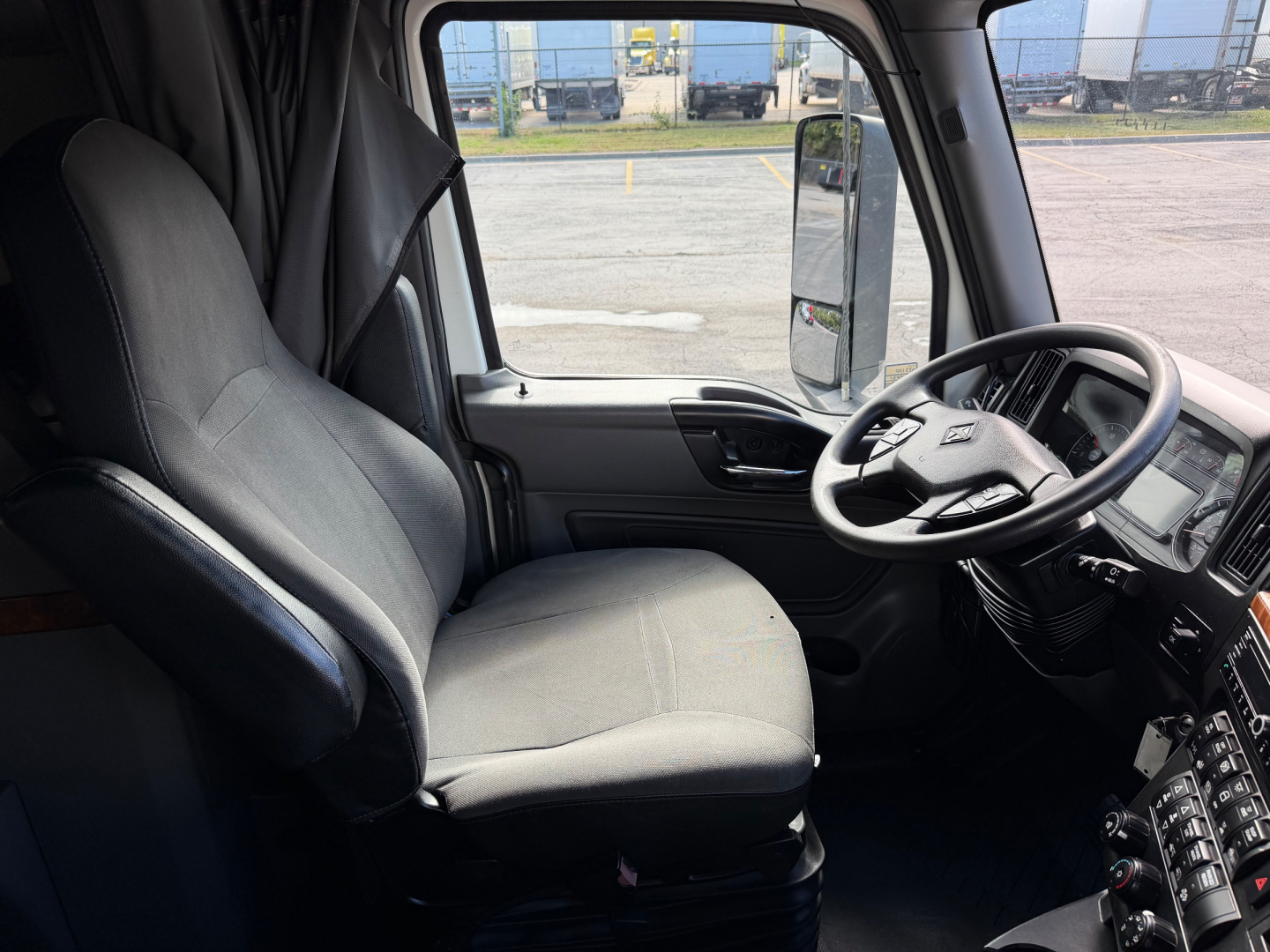 Interior of a 2021 International LT625 truck cab showing driver seat, steering wheel, and dashboard with controls.