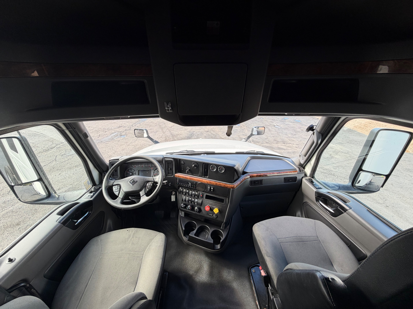 Interior view of a 2021 International LT625 truck cab showing steering wheel, dashboard with controls, center console, and driver and passenger seats.