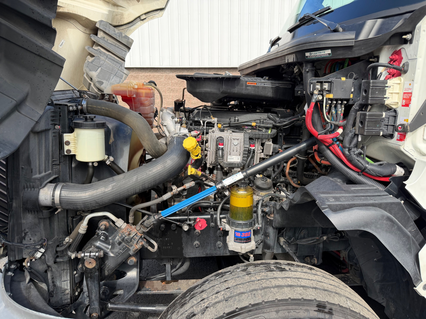 Truck engine bay of a 2021 International LT625 showing engine components, hoses, and a yellow oil filter; visible labels and wiring harnesses.
