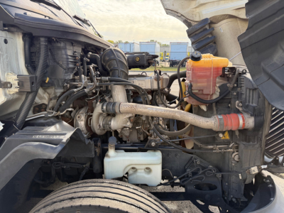 Truck engine bay showing coolant reservoir and various hoses on a 2021 International LT625 engine bay.