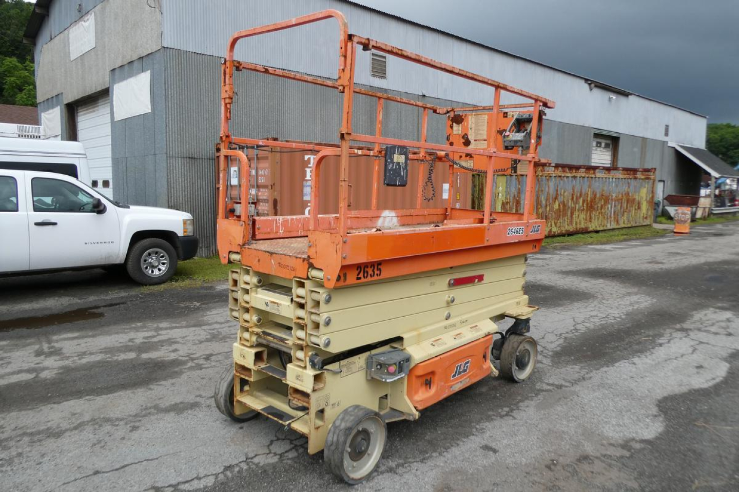 Scissor lift in orange and beige colors showing compact base and platform with safety rails.