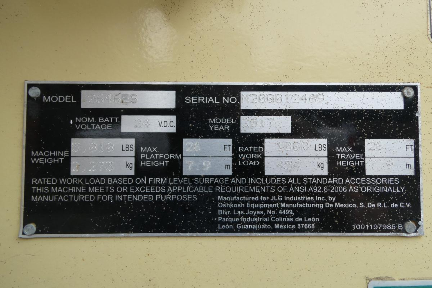 JLG 2646ES equipment identification plate with model and serial number fields, hydraulic specs, and weight/height labels; plate mounted on yellow machinery.
