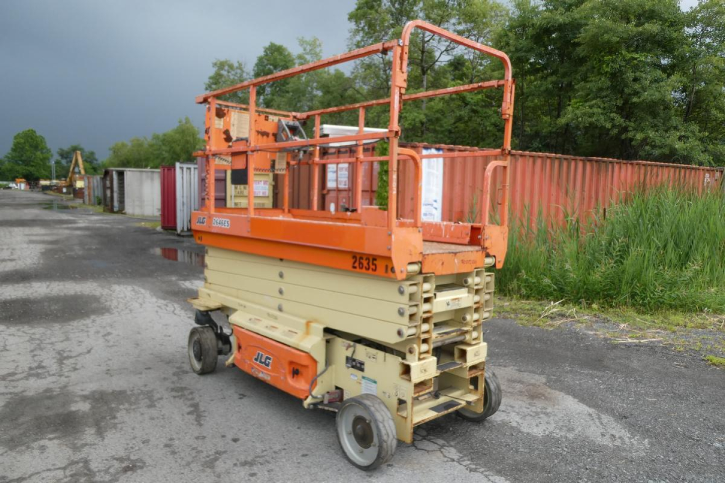 JLG 2646ES scissor lift in an outdoor lot, orange platform rails and tan base, view of rear/side with brand stickers and wheels visible.