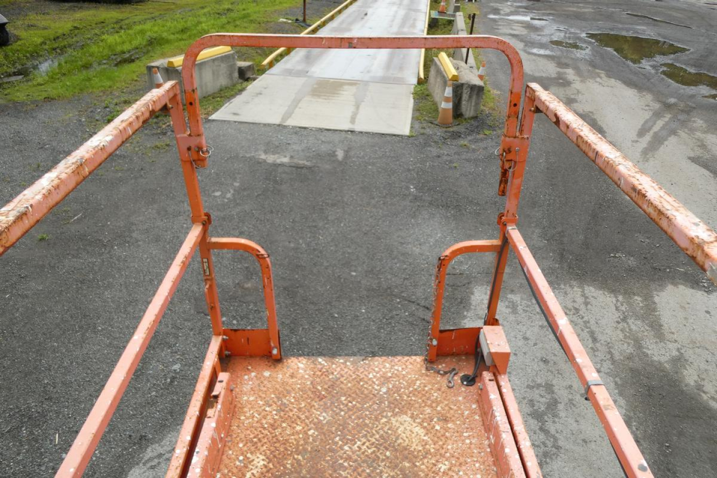 JLG 2646ES scissor lift platform with orange railing and diamond plate deck viewed from above.