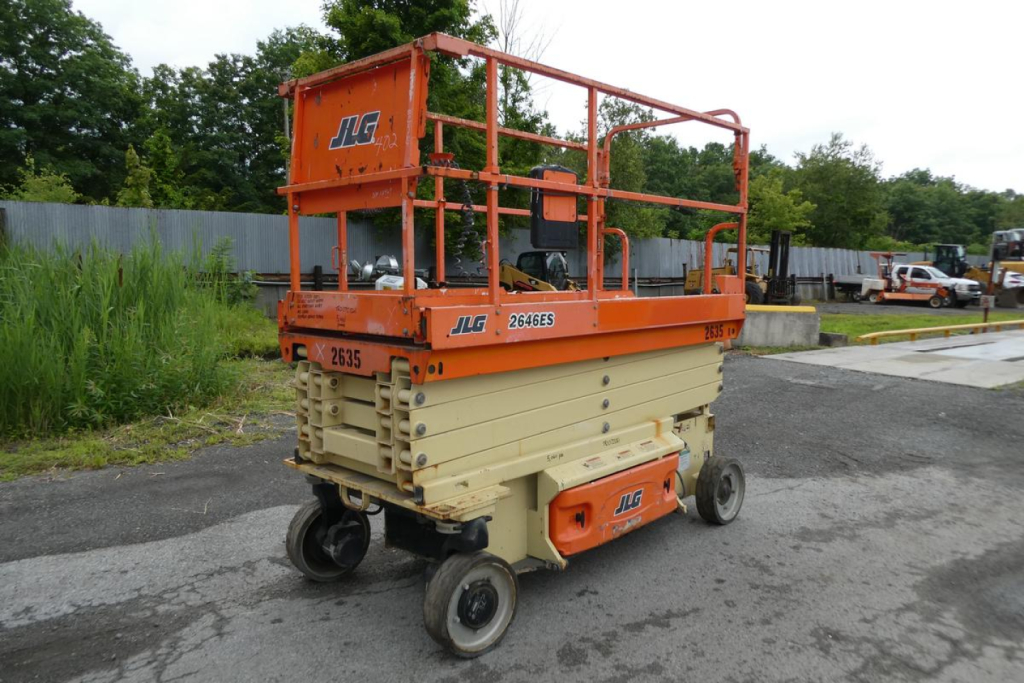 JLG 2646ES scissor lift showing orange guard rails and beige base with wheels, side decals, and identification numbers