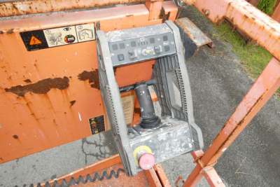 Control panel and joysticks of a JLG 2646ES scissor lift, with orange chassis and warning labels visible on the side.