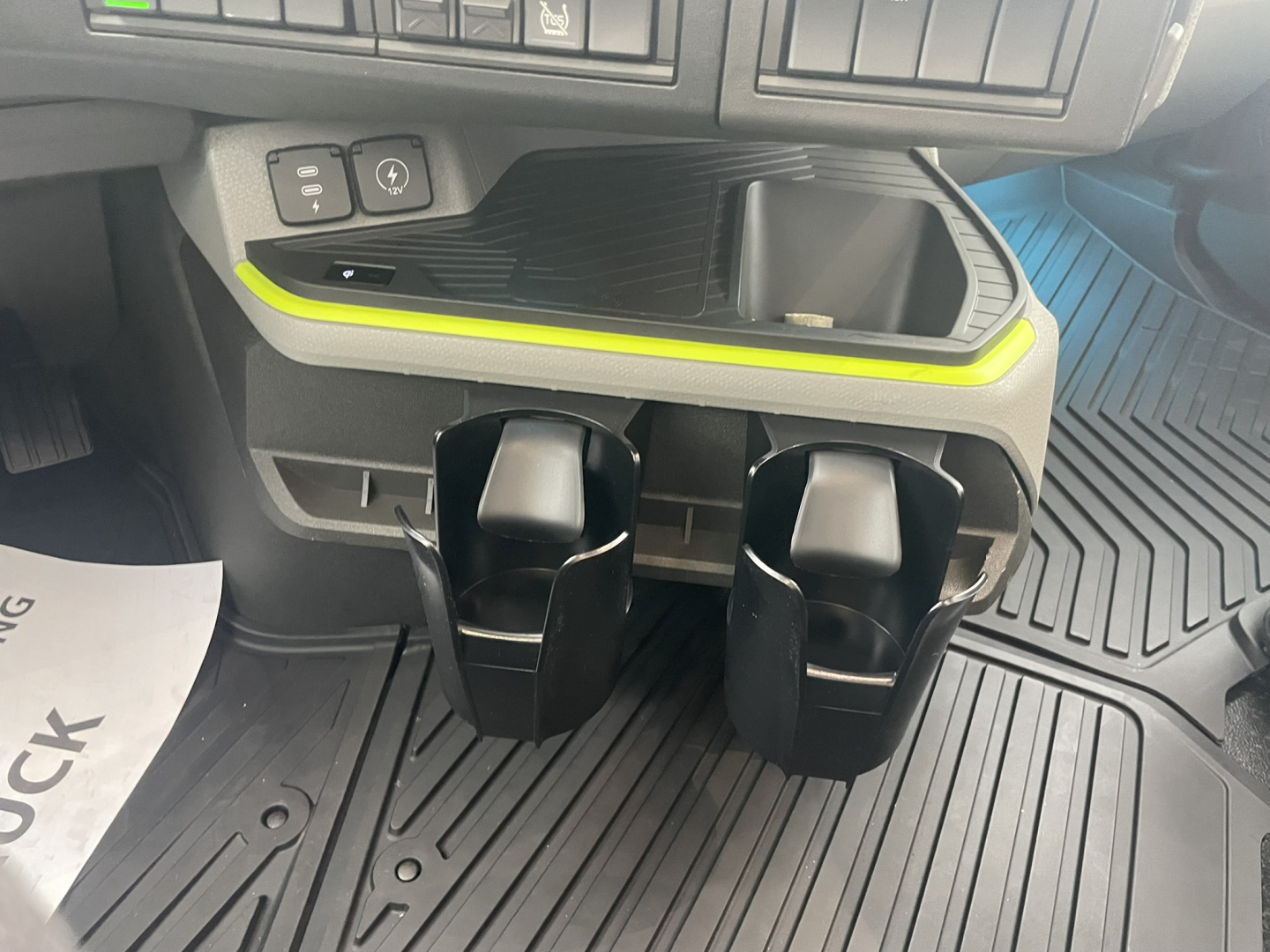 Truck interior center console area with cup holders and storage compartment. Visible text includes dash area controls and a lime-green accent trim.