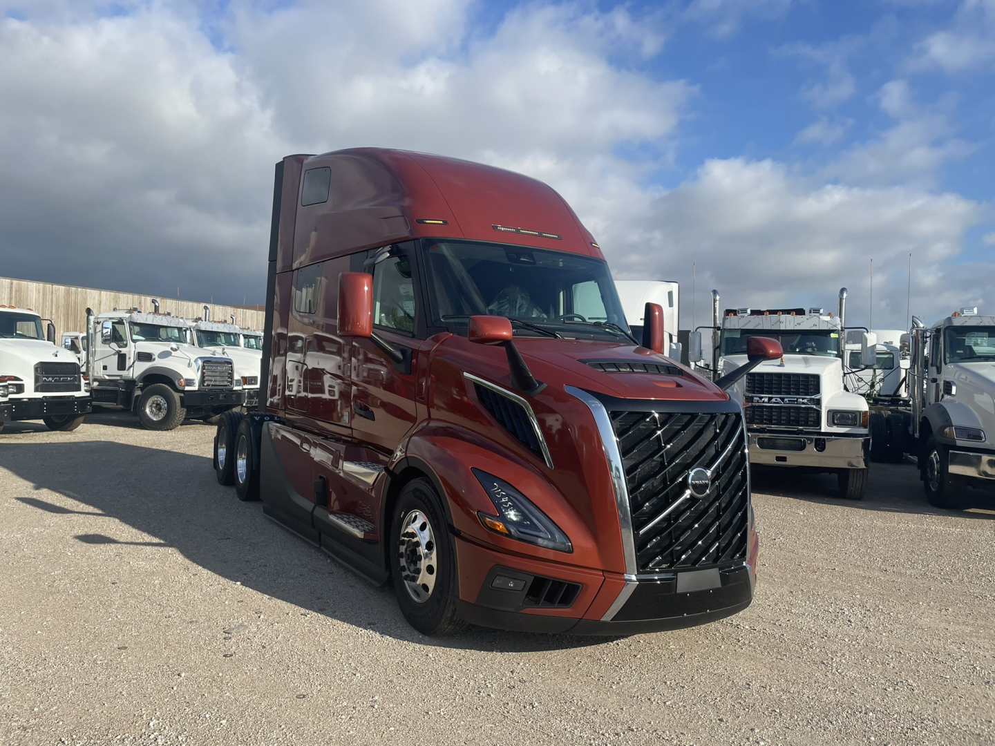 Volvo VNL64T860 sleeper tractor in red, front-left view, with grille and headlights visible, parked among other trucks.