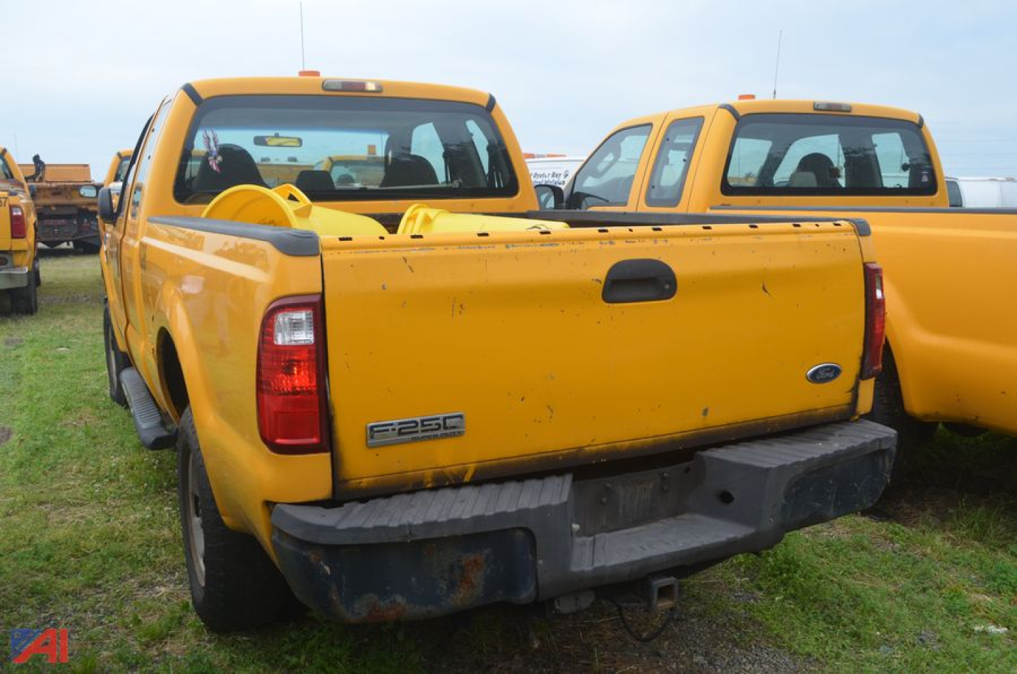 Ford F-250 Super Duty pickup truck rear view showing tailgate with 4x4 badge and spare wheel, yellow two-tone faded paint, extended cab.