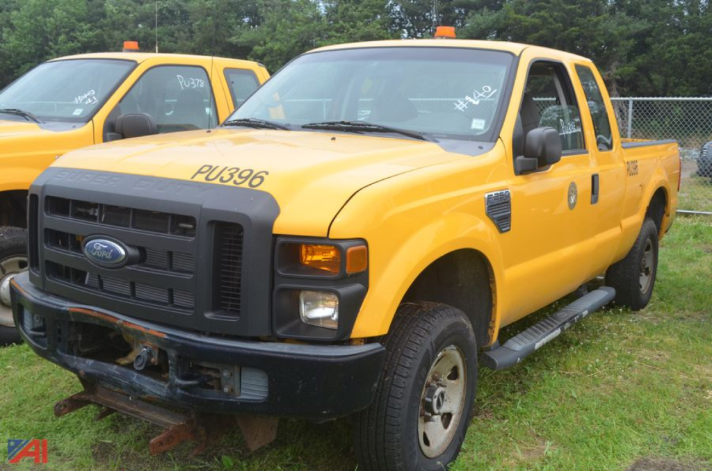 2009 Ford F-250 Super Duty extended cab pickup truck in yellow with black grille; front bumper missing; large side mirrors; step rails visible; truck appears used.