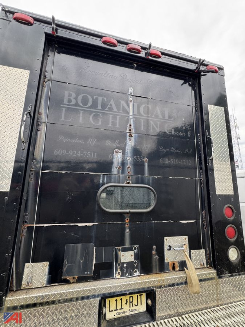 Isuzu NPR box truck rear showing service doors, rusted hardware, diamond plate step bumper, and faded text 'BOTANICAL LIGHTING' on black rear doors.