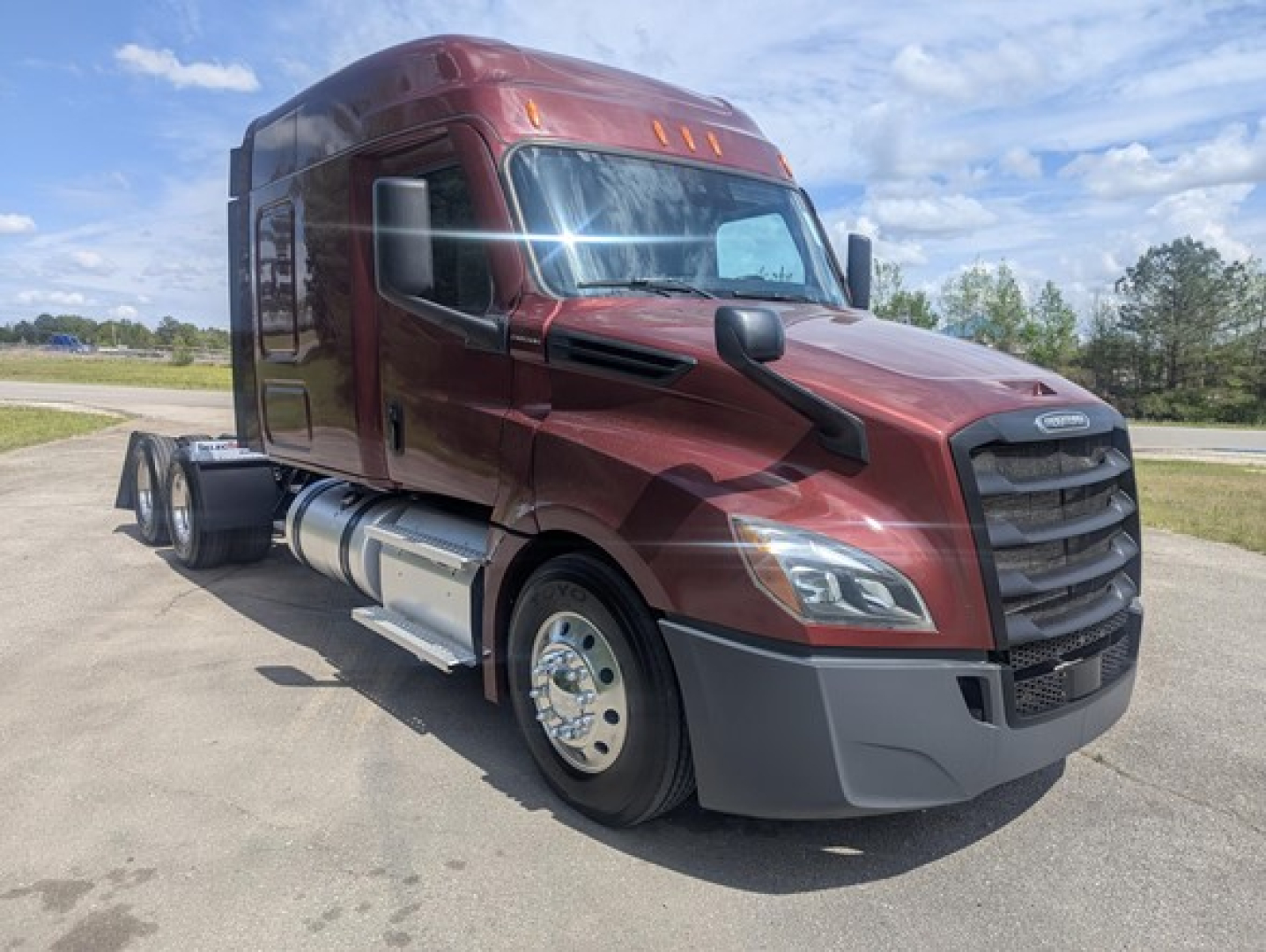 Freightliner Cascadia 126 diesel truck cab front-left view showing maroon exterior and grille