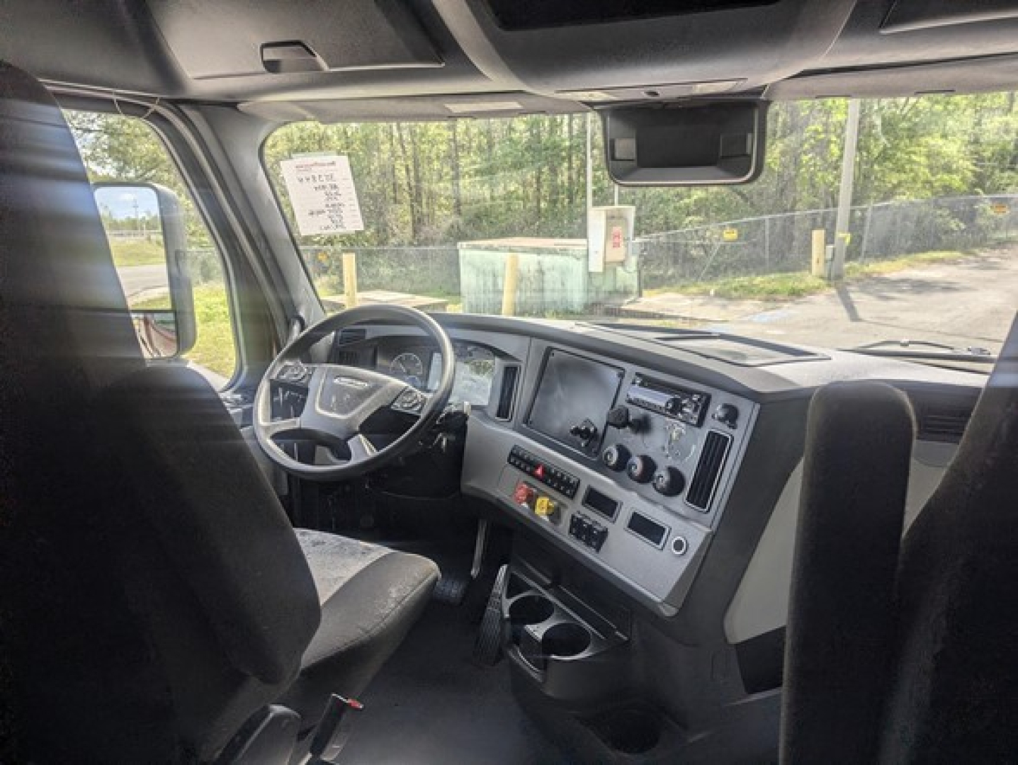 Cab interior of 2022 Freightliner Cascadia 126 with steering wheel, dashboard, and center console in view.