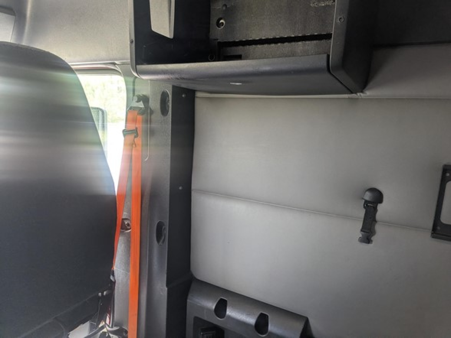 Cab interior of a 2022 Freightliner Cascadia 126 showing vertical grab handle and load area partition.