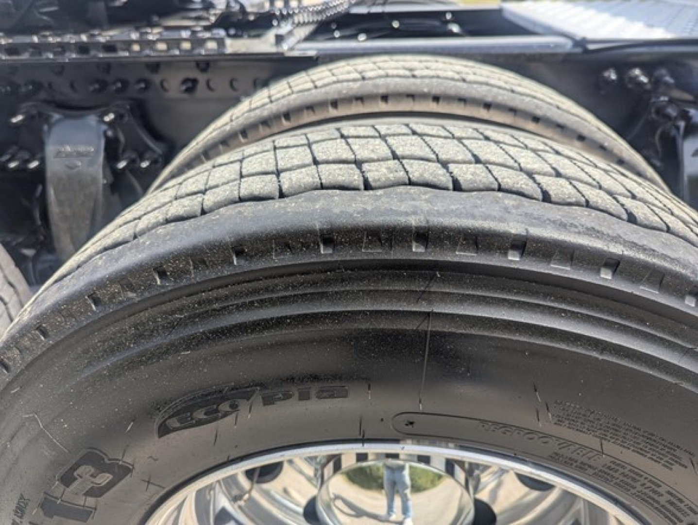 Truck image showing rear wheel, tire, and undercarriage of a Freightliner Cascadia 126 with visible tire treads and suspension components.