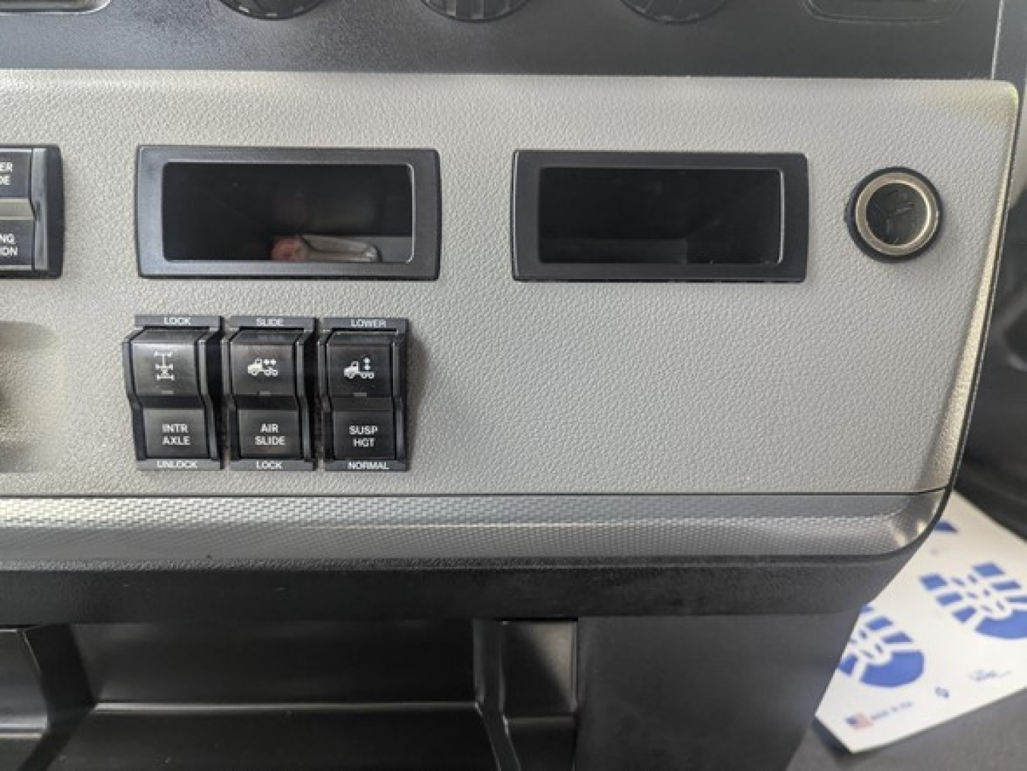 Panel of a 2022 Freightliner Cascadia dashboard showing switches for hitch/air, auxiliary controls and blank slots.