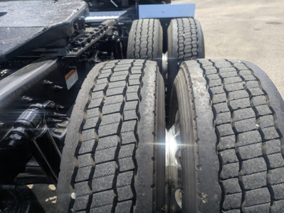 Freightliner Cascadia 126 chassis with dual rear axles and tire tread close-up showing dual tires and suspension components.
