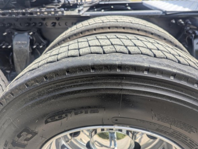 Truck image showing rear wheel, tire, and undercarriage of a Freightliner Cascadia 126 with visible tire treads and suspension components.