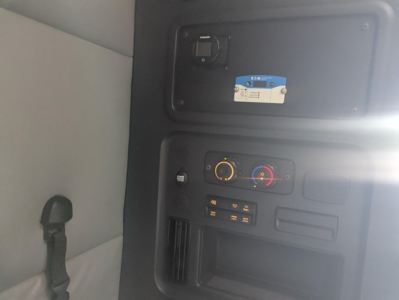 Freightliner Cascadia dashboard area showing control panel with switches, climate dials, and a blue label on a panel.