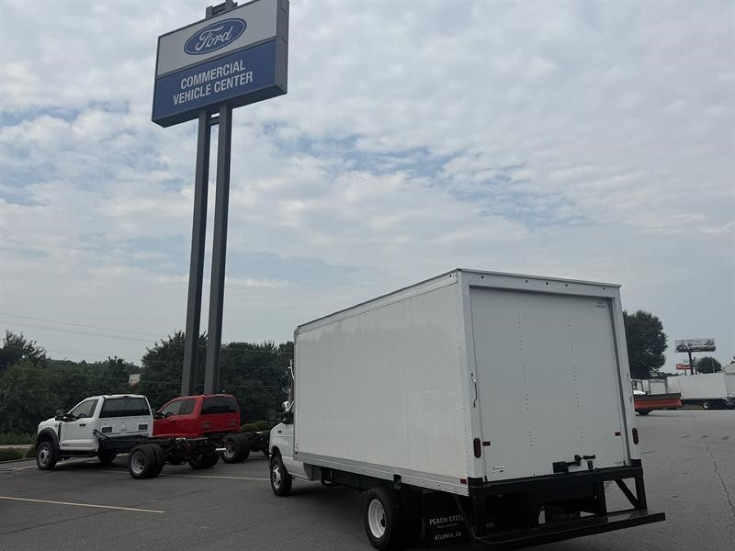 Ford commercial vehicle center sign with a white box truck in a lot. Visible text on sign includes Ford logo and 'Commercial Vehicle Center'.