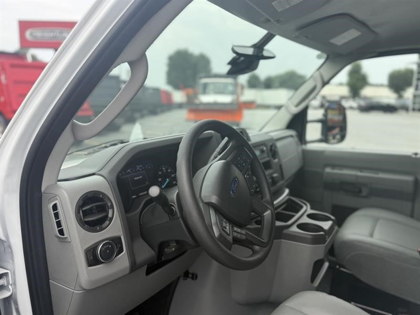 Ford E-450 interior cab view showing steering wheel and dashboard with cup holders and center console.