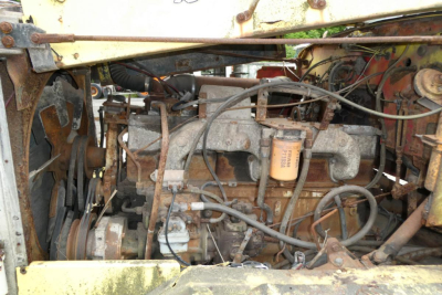 Autocar cab cut truck engine bay showing exposed engine with hoses, filter, belts, and wiring in a weathered compartment.